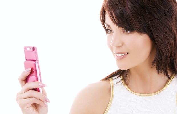 A woman smiles at the screen of the mobile phone in her hand